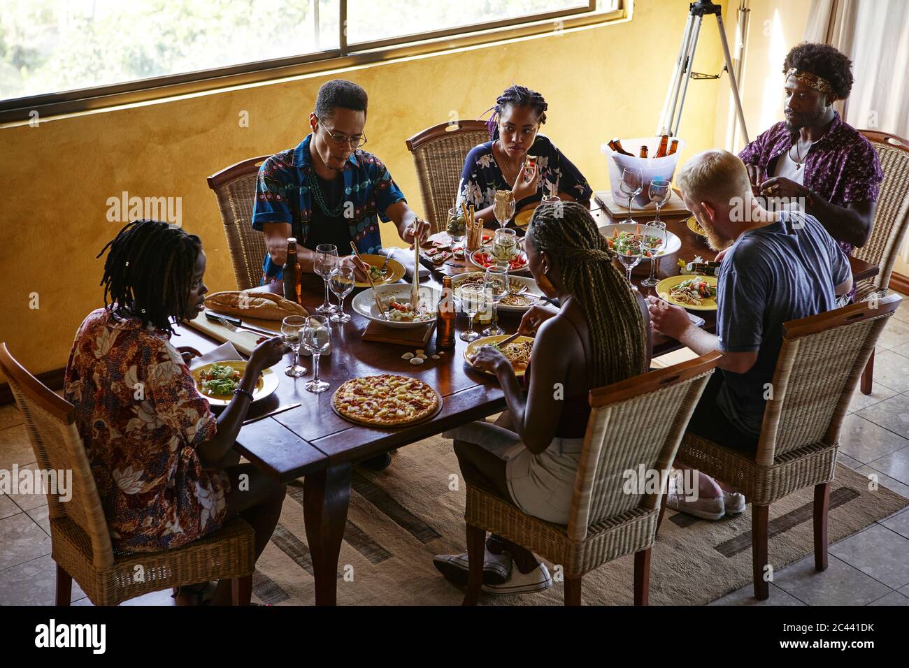 Blick auf Freunde, die beim Essen am Esstisch sitzen und das Mittagessen genießen Stockfoto