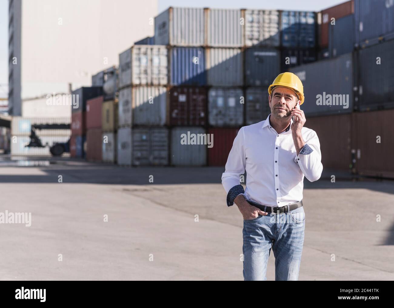 Geschäftsmann am Telefon trägt Schutzhelm auf Industriegelände Stockfoto
