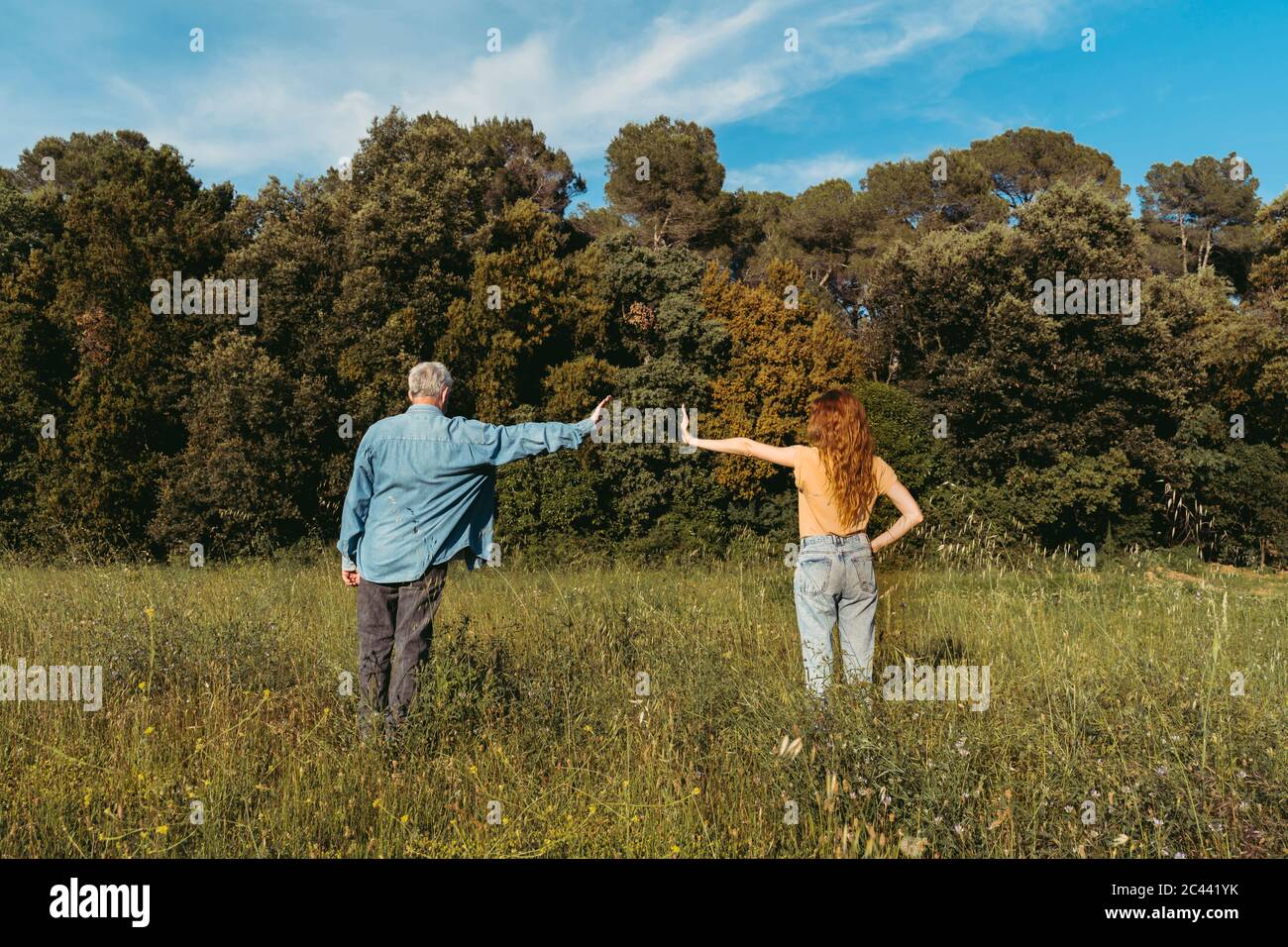 Rückansicht von Frau und älterer Mann mit Masken auf der Wiese stehen, Sicherheitsabstand Stockfoto