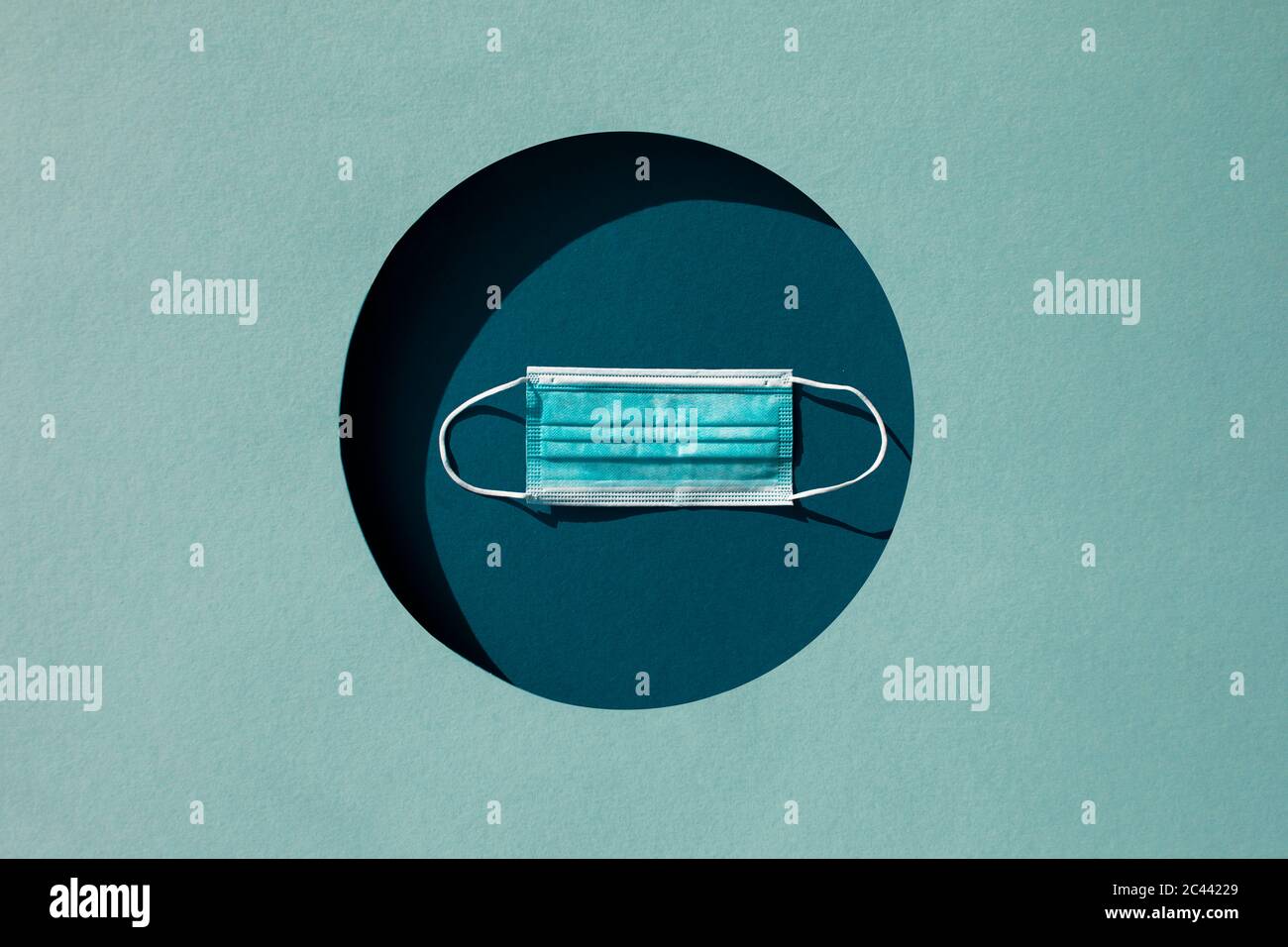 Studio Schuss von schützenden Gesichtsmaske in kreisförmigen Papier geschnitten Loch Stockfoto