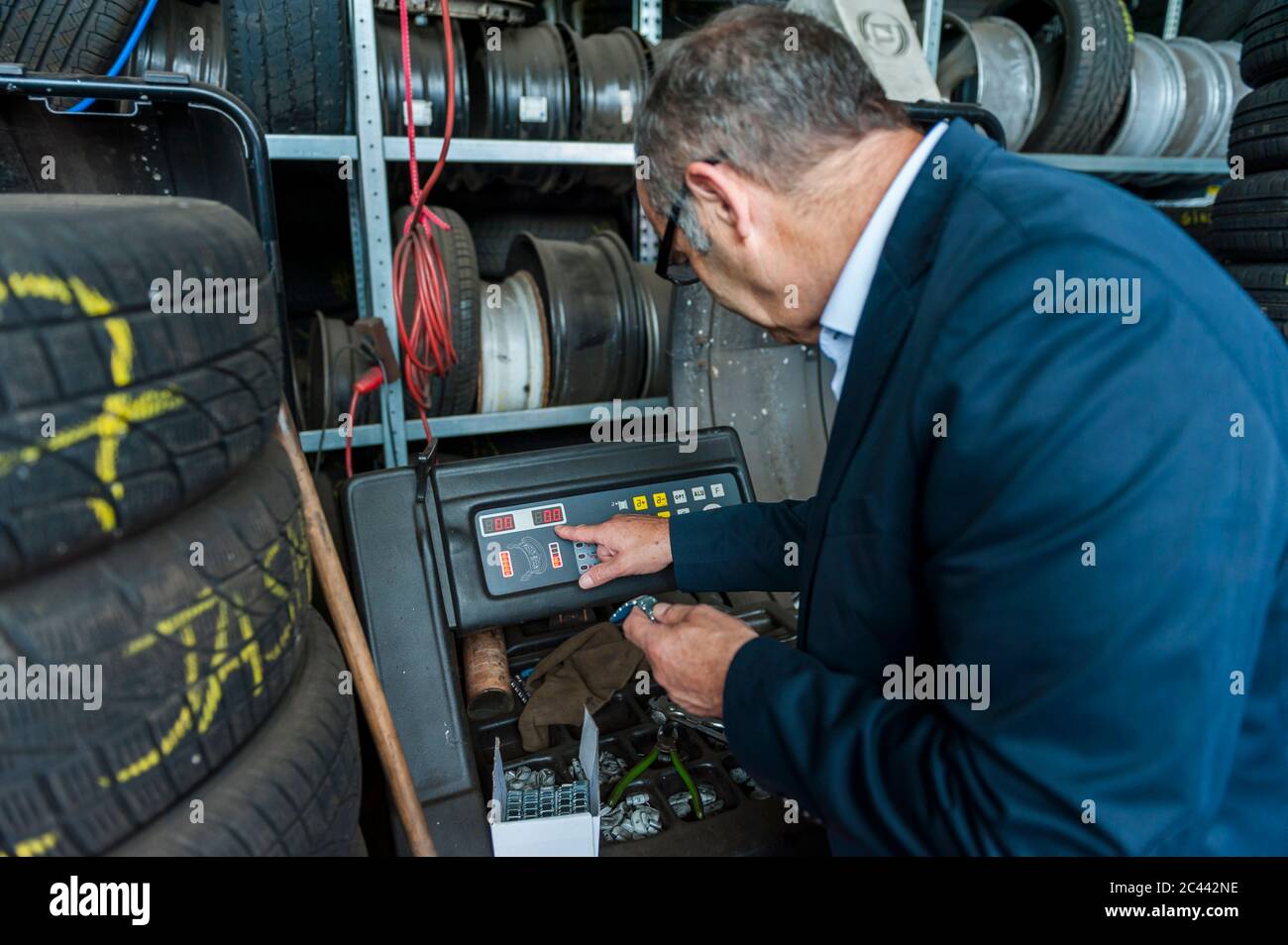 Senior männlichen Unternehmer mit Maschinen von Reifen im Geschäft Stockfoto