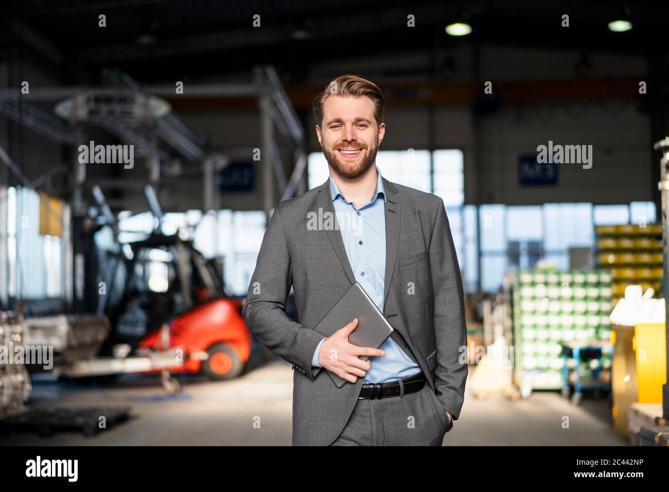 Porträt eines lächelnden jungen Geschäftsmannes mit Tablet in einer Fabrik Stockfoto