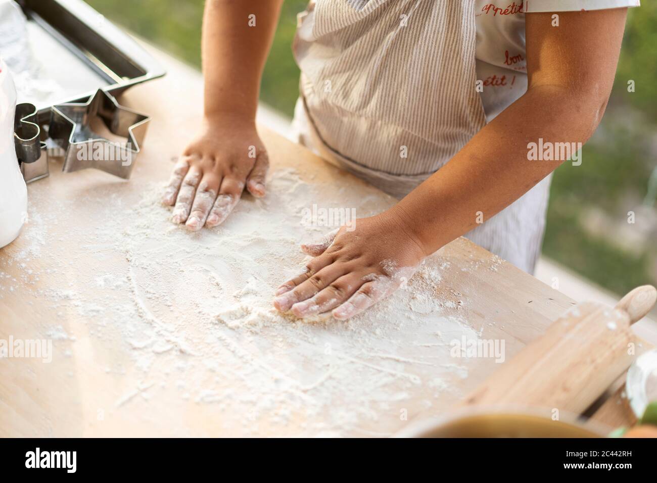 Junge Hände verteilen Mehl auf Küchentisch Stockfoto