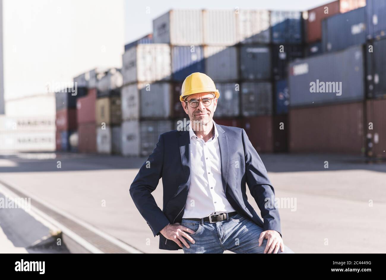 Porträt eines lächelnden Geschäftsmannes mit Schutzhelm auf dem Industriegelände Stockfoto