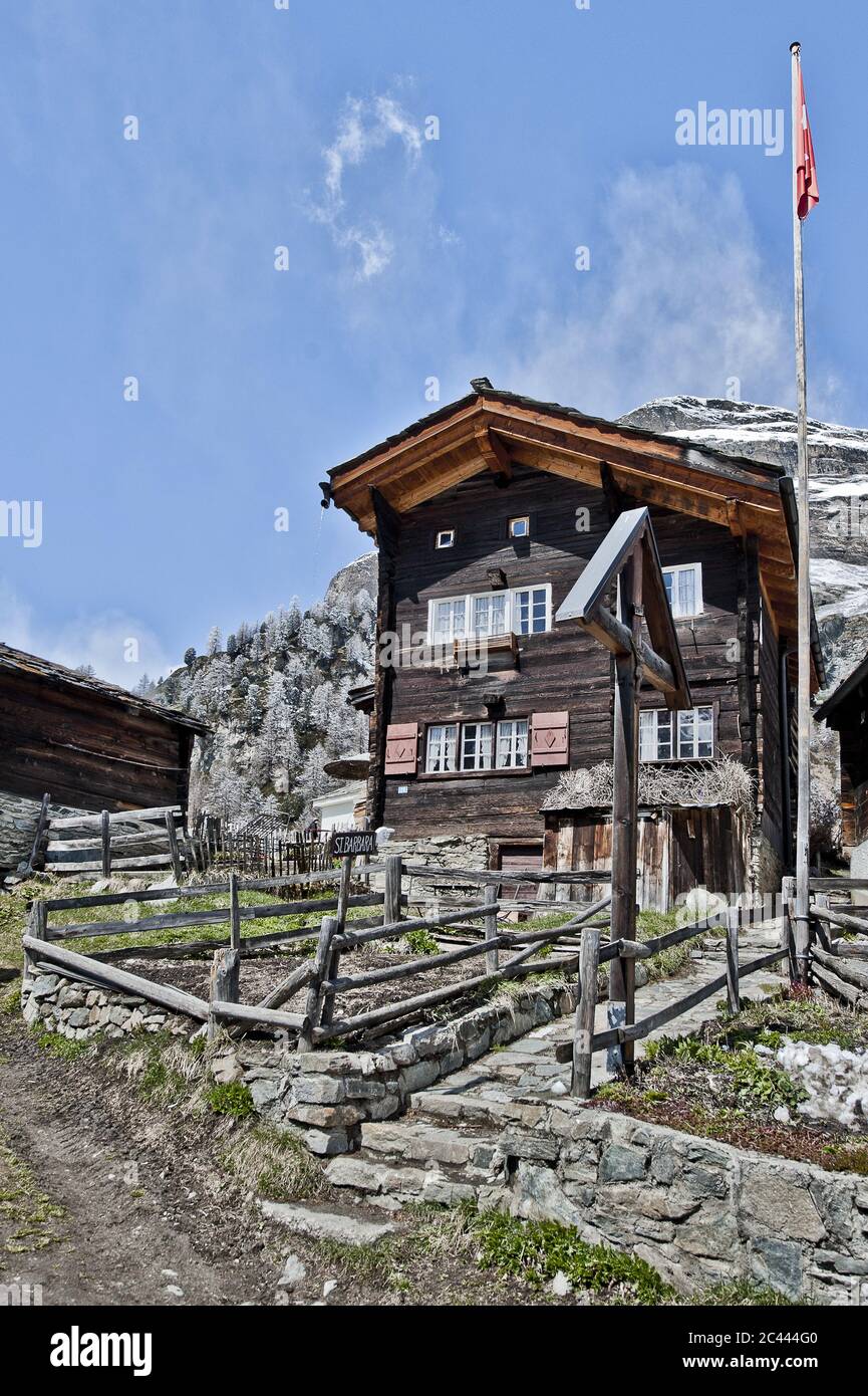 Holzhaus mit Schweizer Flagge und Alpenlandschaft, Zermatt, Schweiz Stockfoto