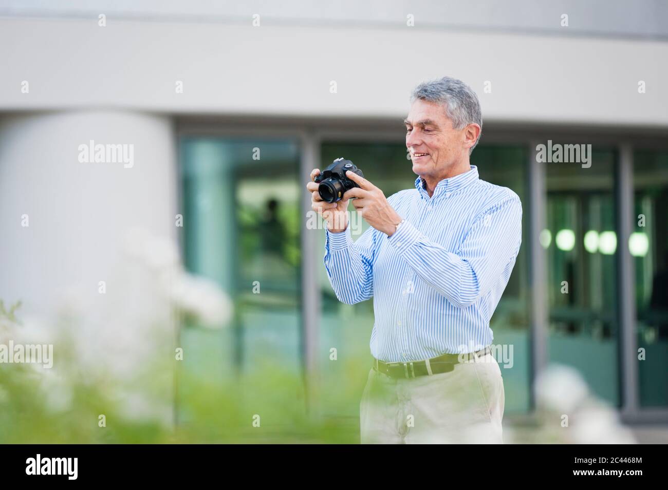 Porträt eines lächelnden Geschäftsmannes mit Digitalkamera im Freien Stockfoto