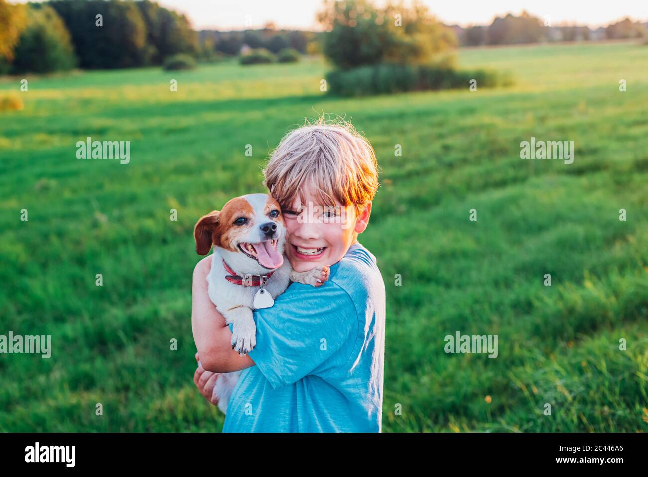 Porträt der glückliche junge mit Hund auf dem Feld während der sonnigen Tag, Polen Stockfoto