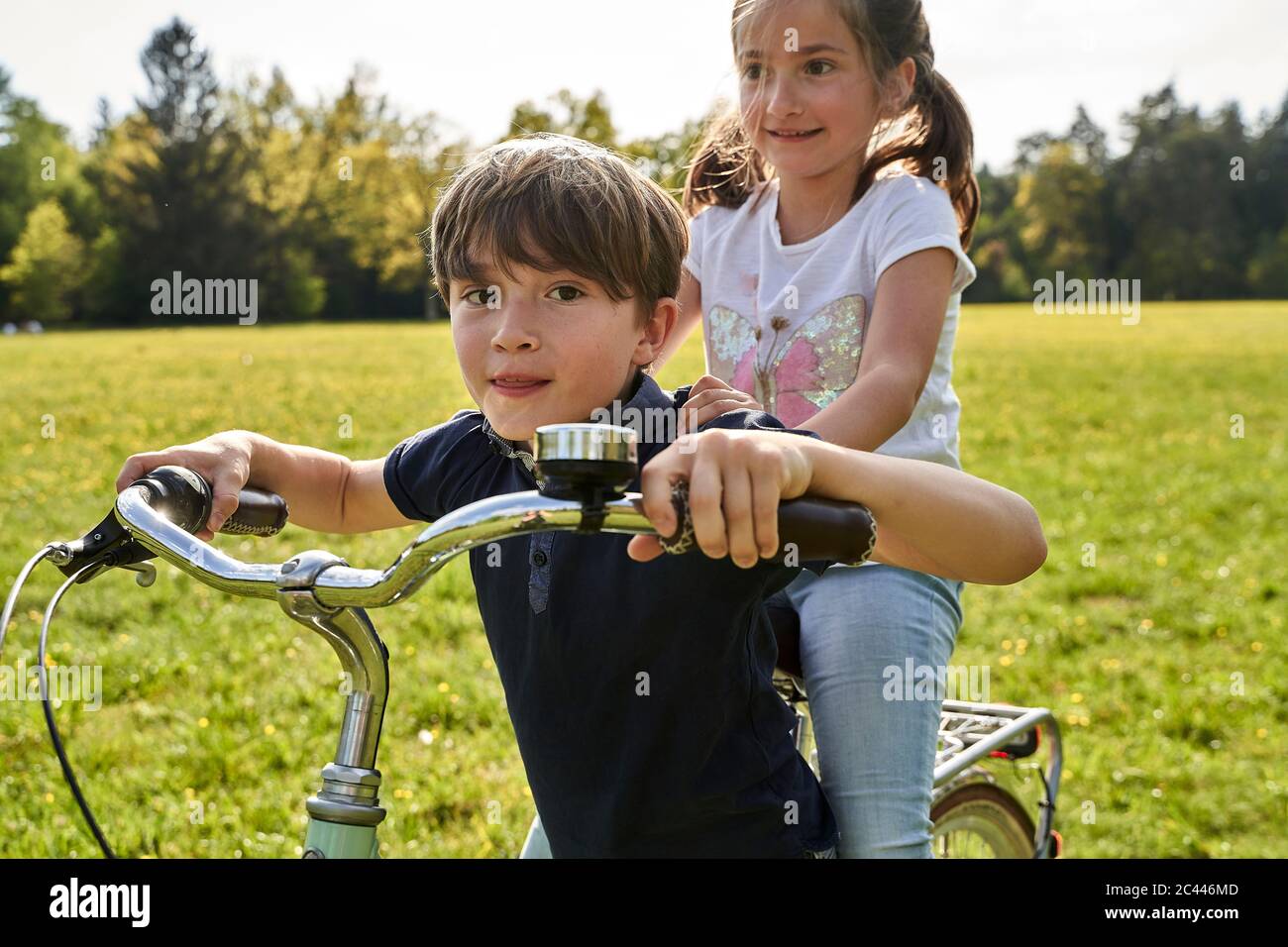 Junge geben Schwester Fahrrad fahren an sonnigen Tag Stockfoto