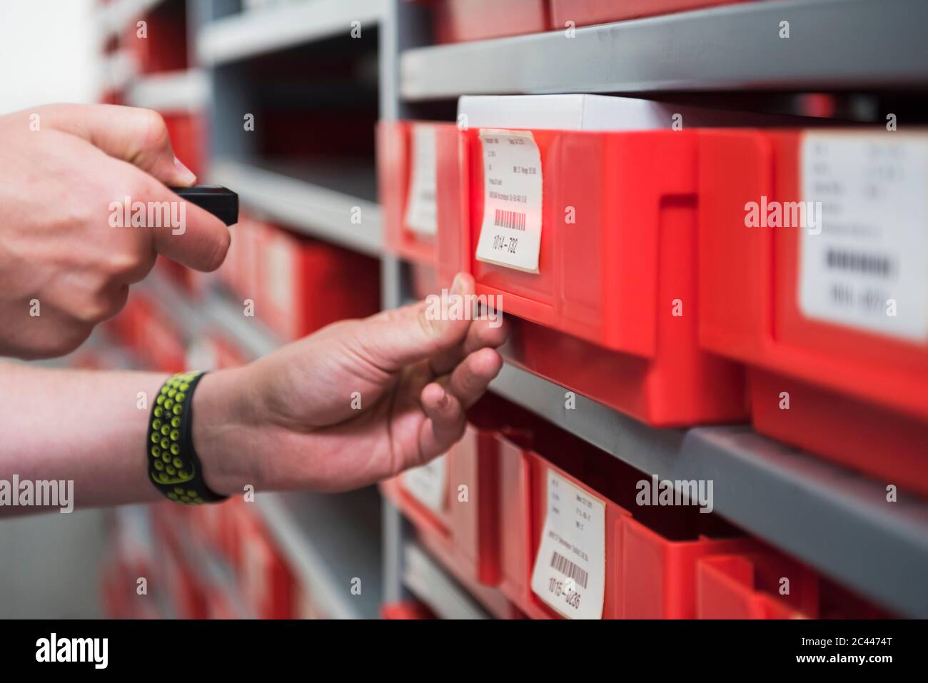Nahaufnahme eines Mannes im Lagerhaus einer Fabrik mit einem kleinen Scanner Stockfoto