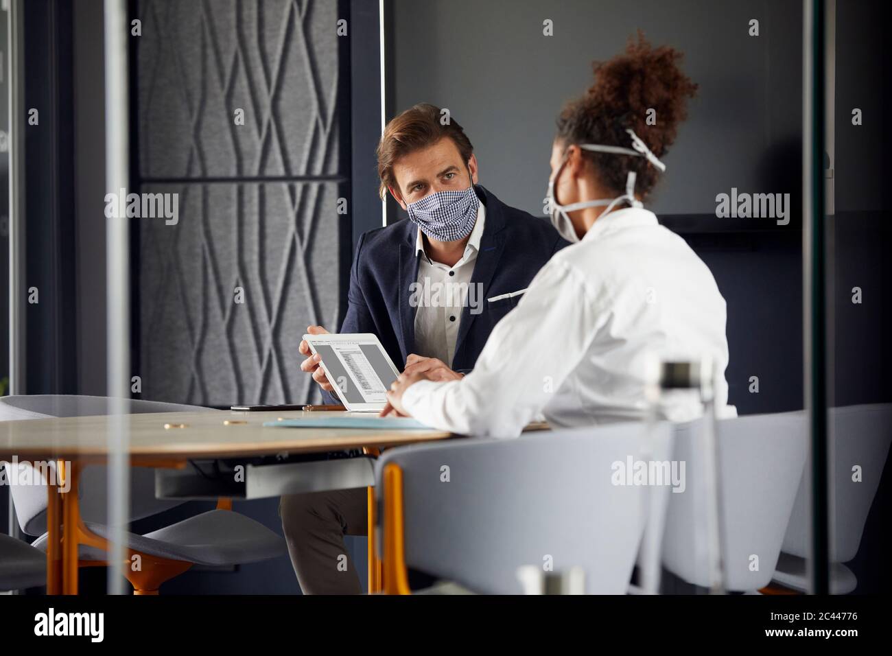 Geschäftsmann, der während der Krise in Cororna Kunden im Büro berät Stockfoto