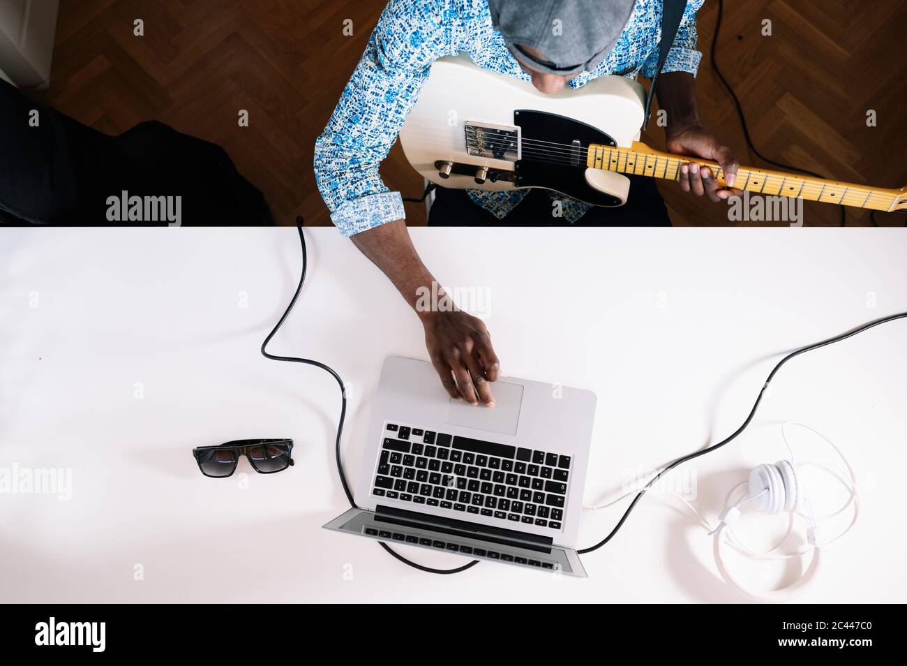 Junger Mann, der zuhause aus dem Internet Gitarre spielen lernt Stockfoto