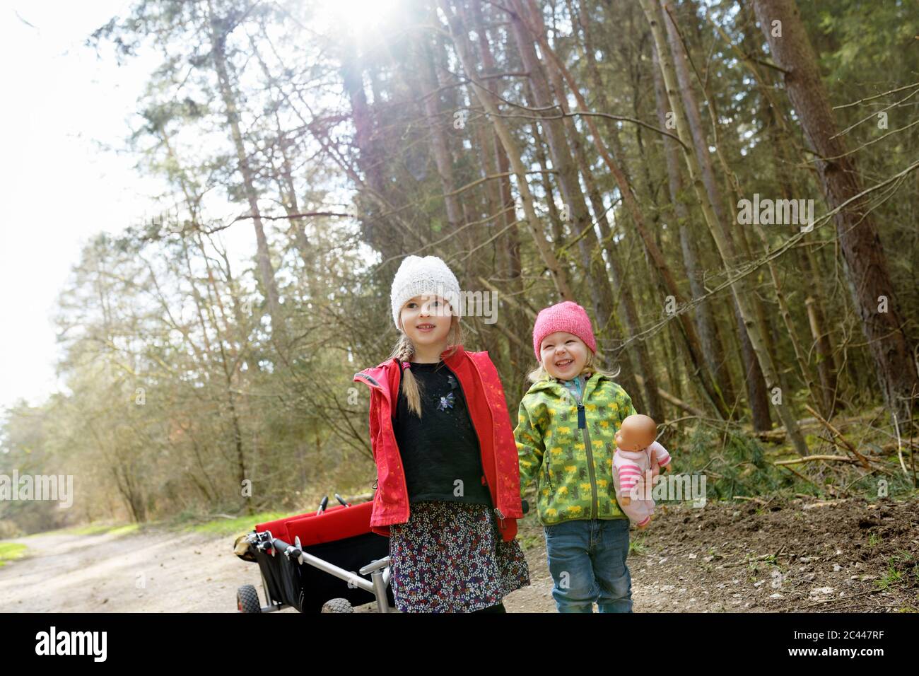 Zwei kleine Schwestern ziehen Trolley auf Waldweg Stockfoto