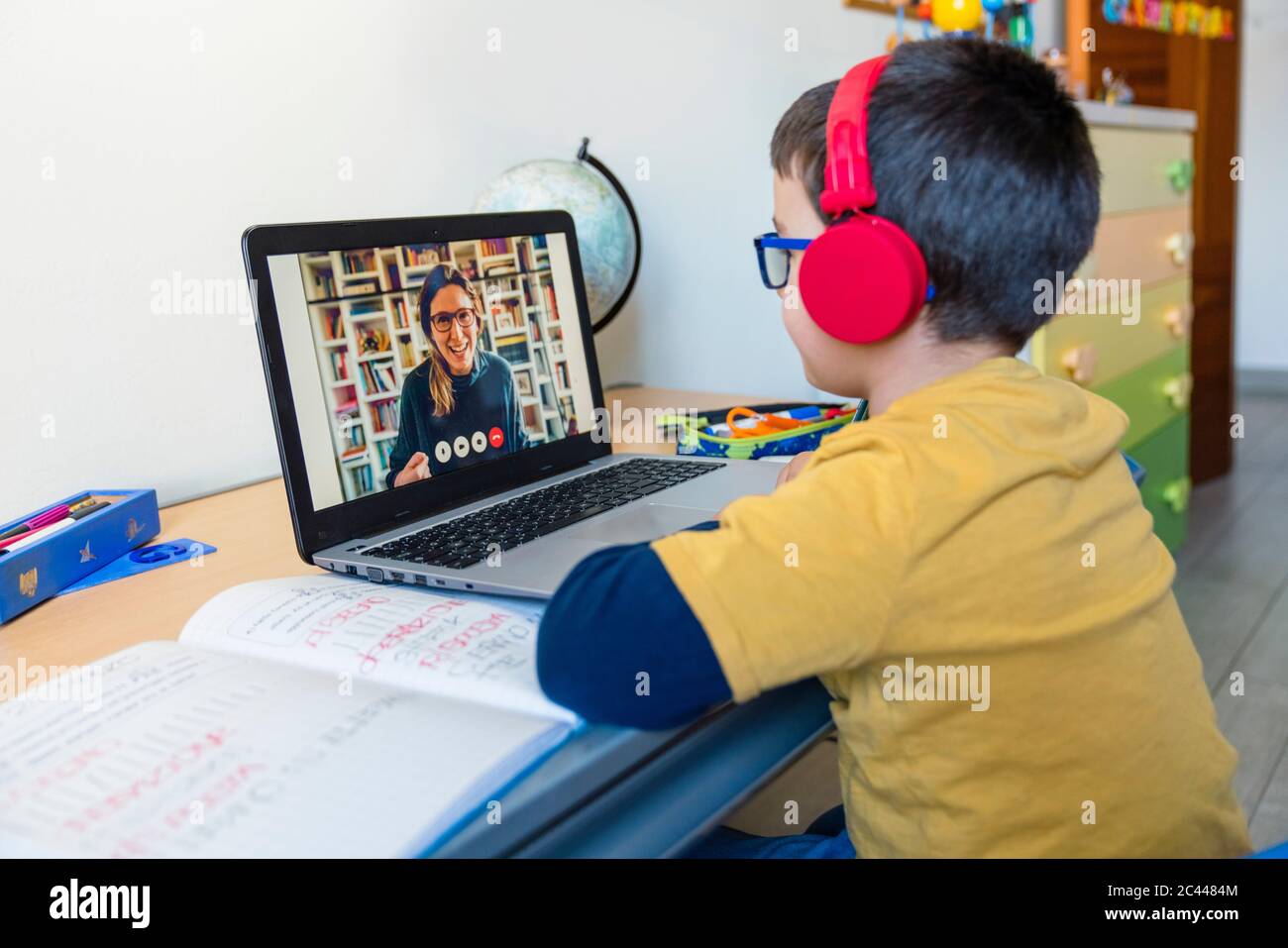 Junge hören Lehrer über Kopfhörer während Videoanruf zu Hause Stockfoto