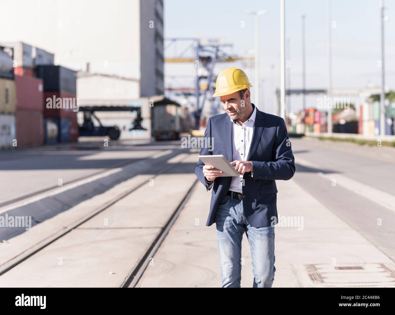 Geschäftsmann trägt Schutzhelm mit digitalen Tablet auf Industriegelände Stockfoto