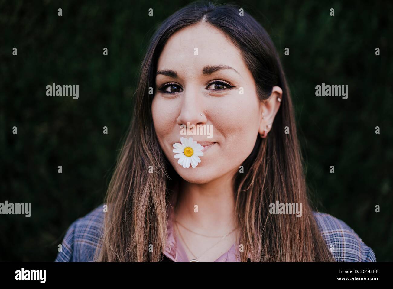 Porträt einer lächelnden Frau mit marguerite im Mund Stockfoto