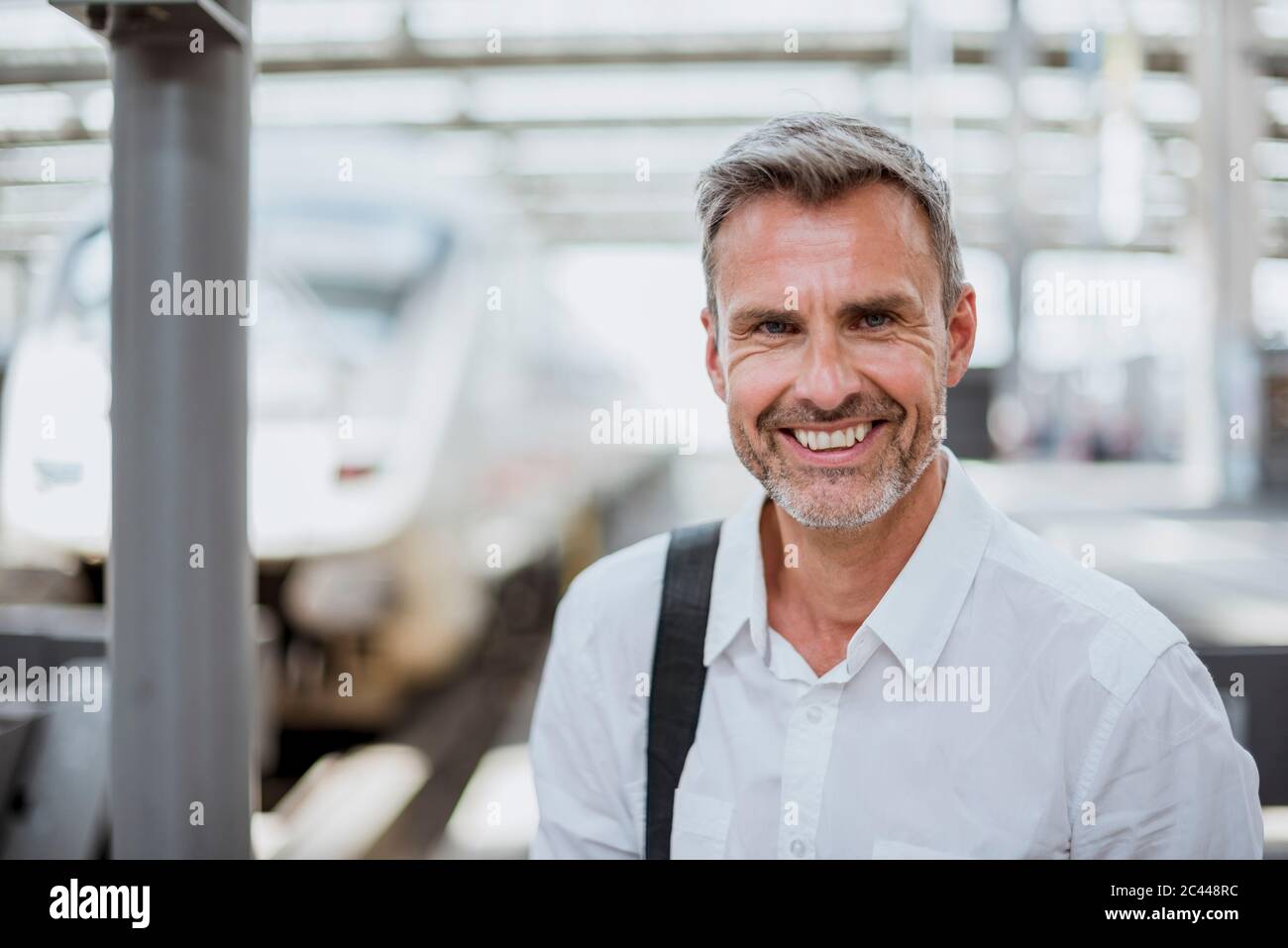 Nahaufnahme eines lächelnden Geschäftsmannes am Bahnhofssteig Stockfoto