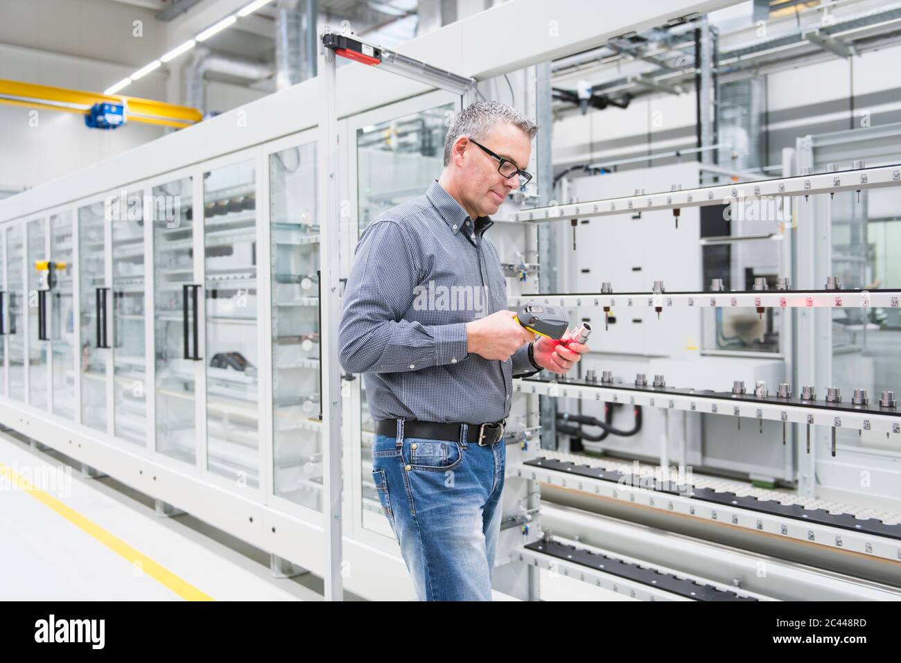 Mann, der in einer Fabrik einen Barcode-Scanner an einem Produkt verwendet Stockfoto