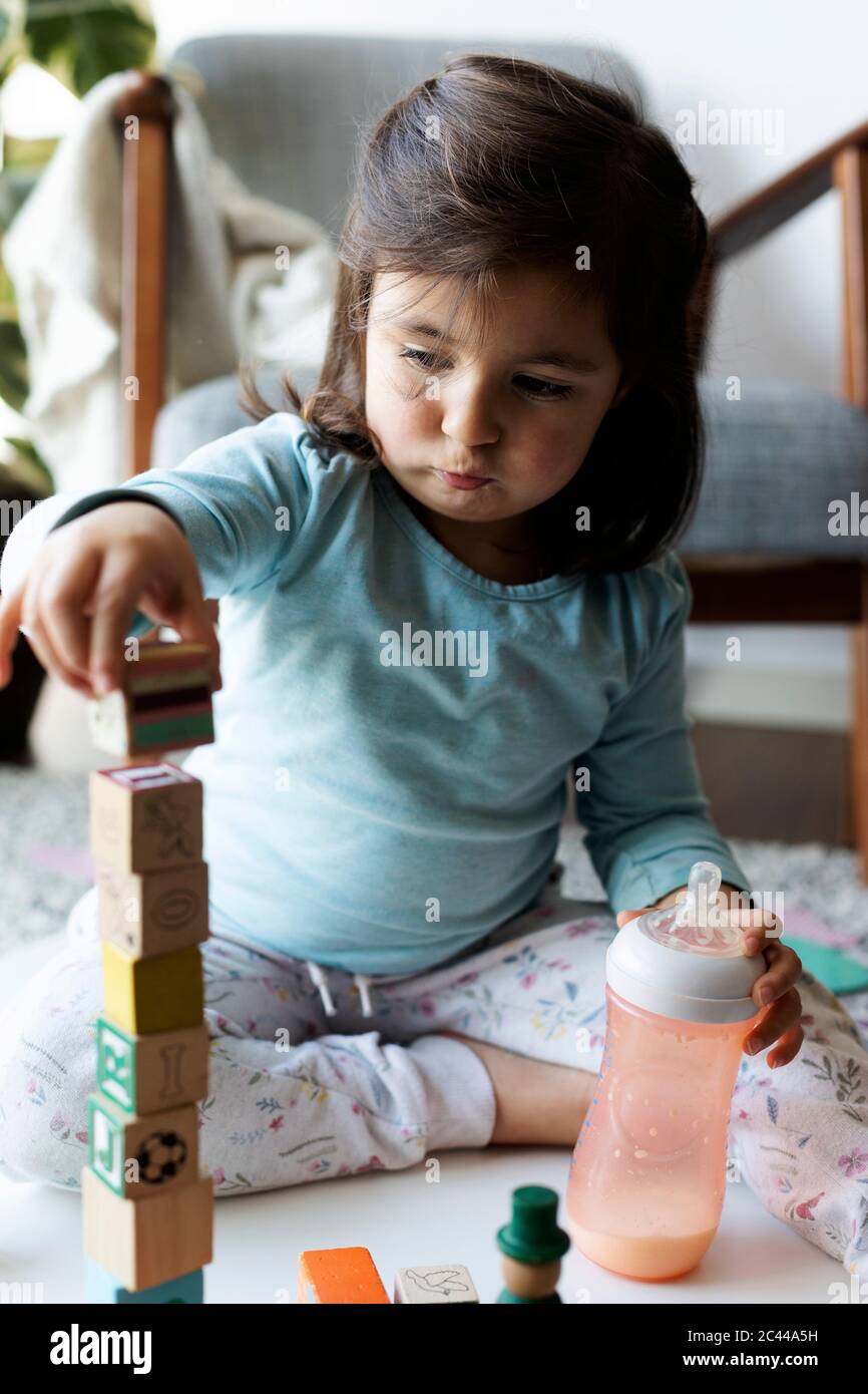 Portrait of Kleinkind Mädchen auf dem Boden sitzen spielen mit hölzernen Bausteinen Stockfoto