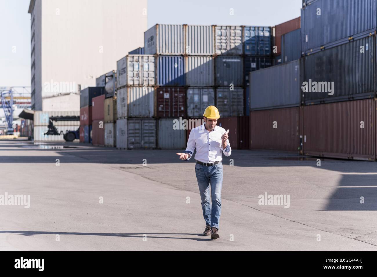 Geschäftsmann trägt Schutzhelm mit Handy auf Industriegelände Stockfoto