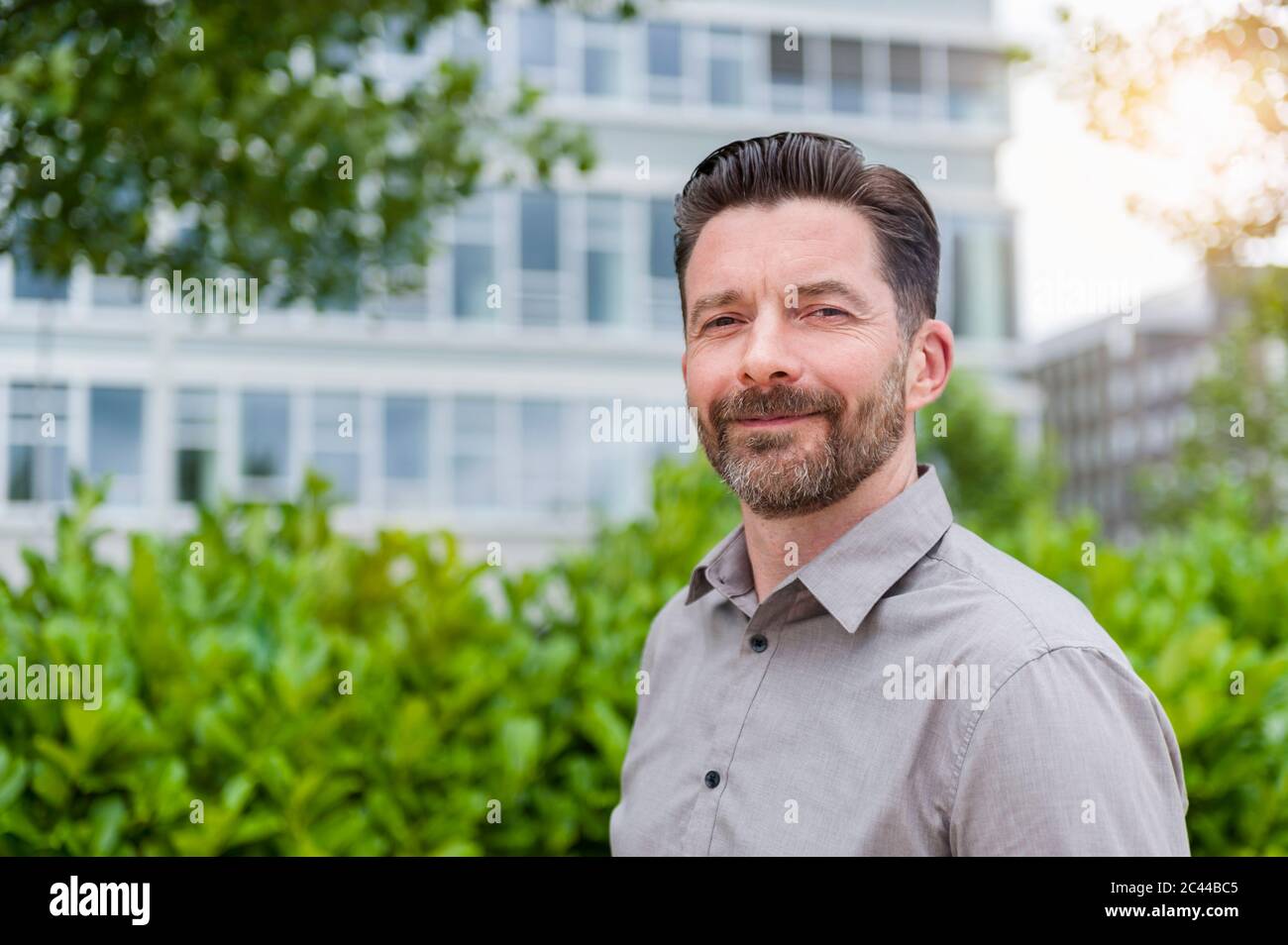 Porträt eines lächelnden, gut aussehenden bärtigen Geschäftsmannes im Finanzviertel Stockfoto