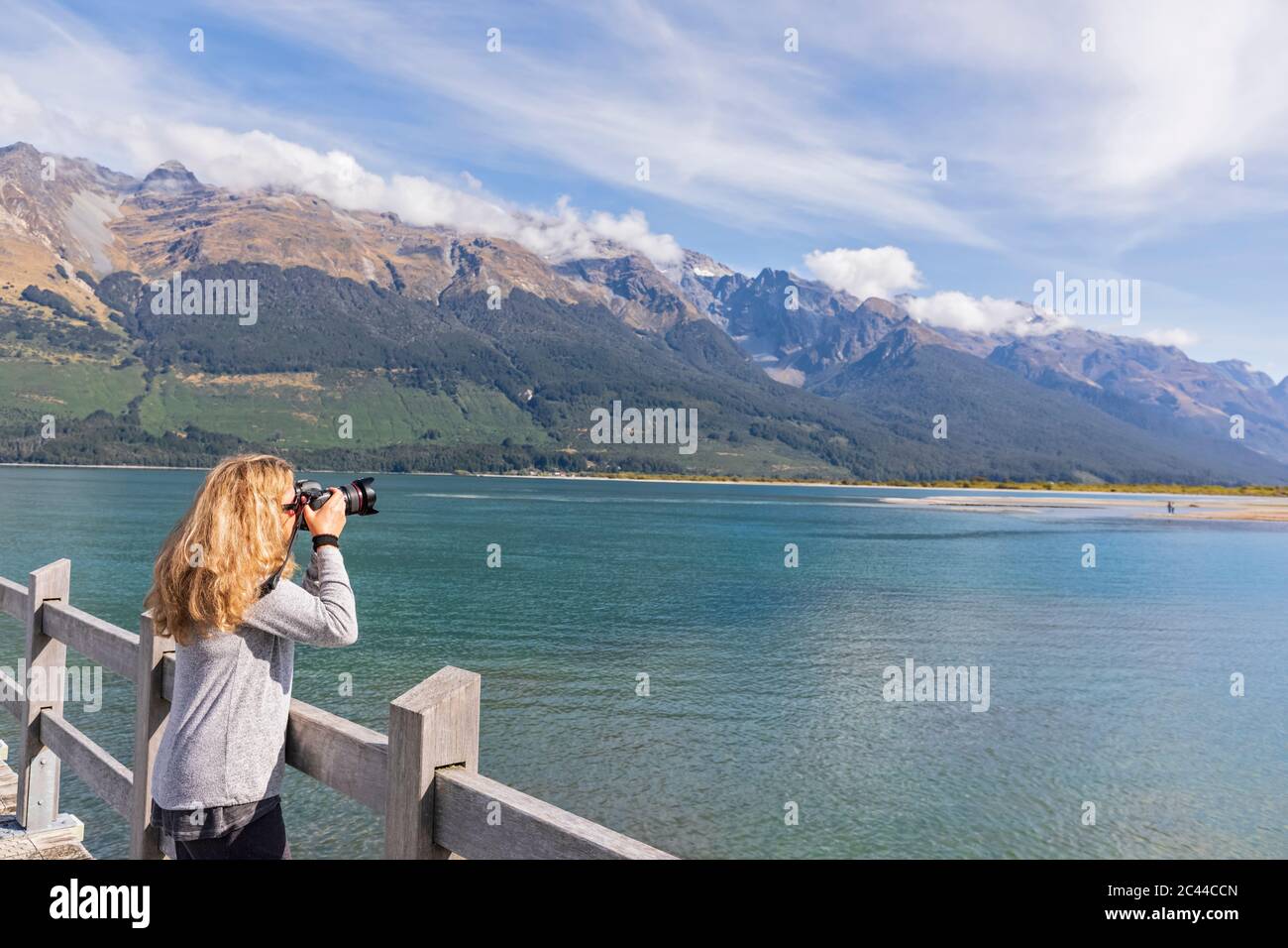Neuseeland, Ozeanien, Südinsel, Otago, Lake Wakatipu, Neuseeland Alpen, Glenorchy, Frau fotografiert Landschaft vom Pier Stockfoto