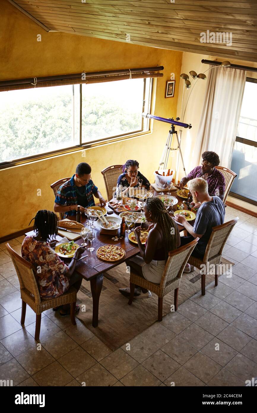 Man hat einen Blick auf Freunde, die beim Essen am Esstisch sitzen Stockfoto