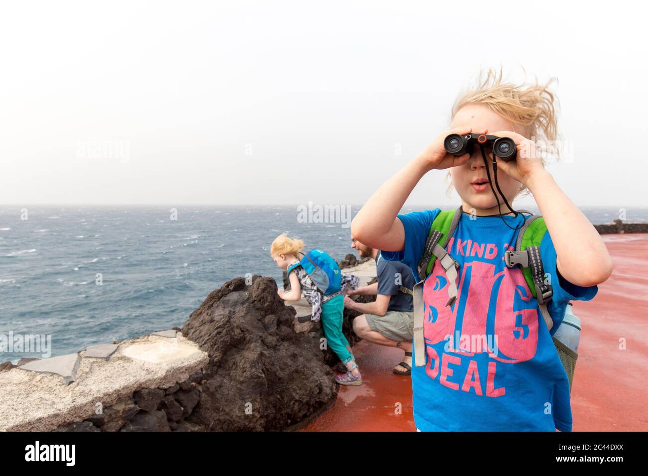 Neugieriger Junge, der durch das Fernglas schaut, während er im Urlaub mit der Familie an der Costa Adeje, Kanarische Inseln, Spanien genießt Stockfoto