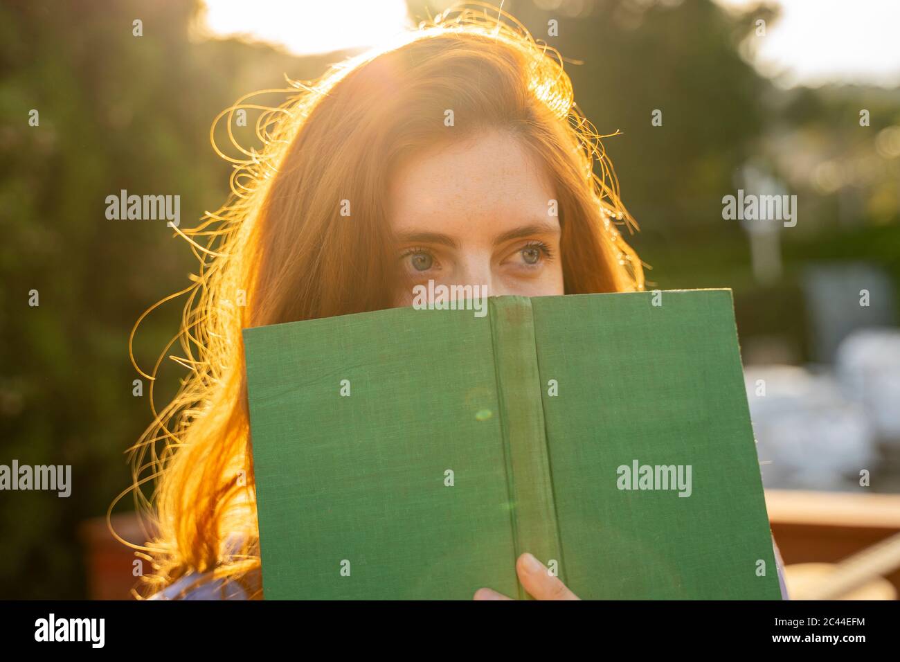 Porträt einer rothaarigen Frau mit grünem Buch Stockfoto