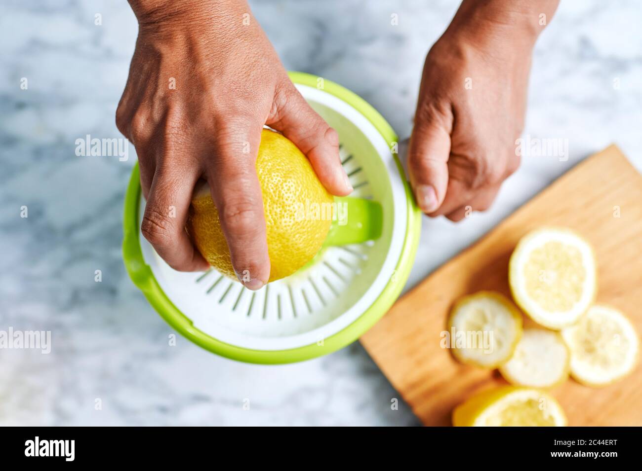 Hände einer Frau, die Zitronen mit dem Entsafter zusammendrückt Stockfoto
