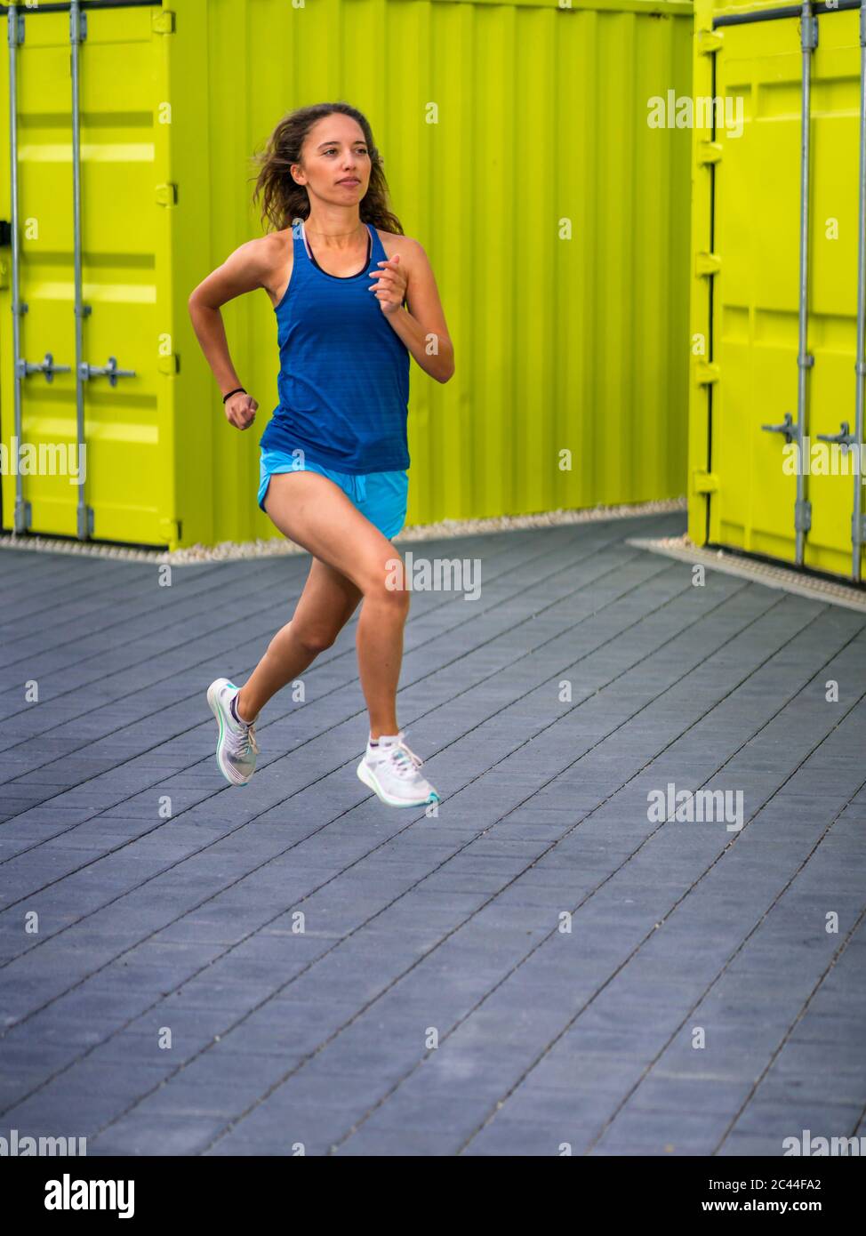 Junge Frau joggen auf bürgersteig vor Cargo Container Stockfoto