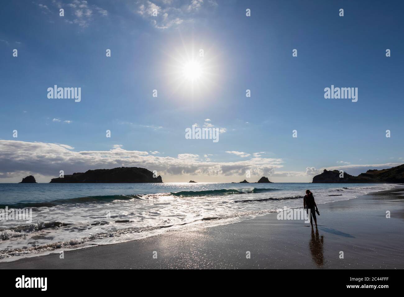 Neuseeland, Nordinsel, Waikato, Sonne über Silhouette der Frau allein auf Hahei Beach glänzend Stockfoto