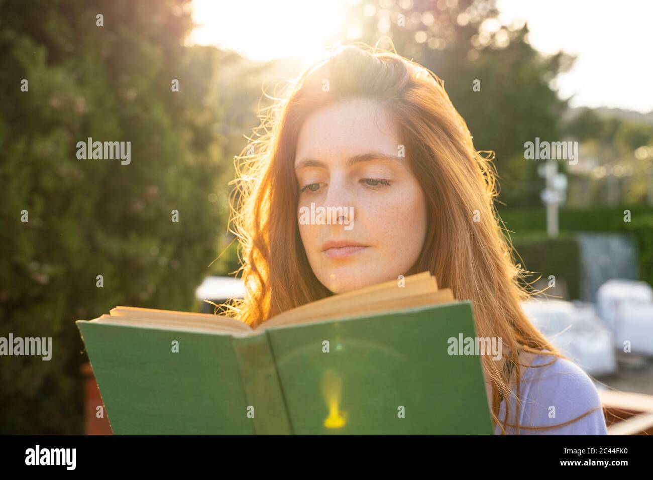 Porträt einer rothaarigen Frau mit grünem Buch Stockfoto