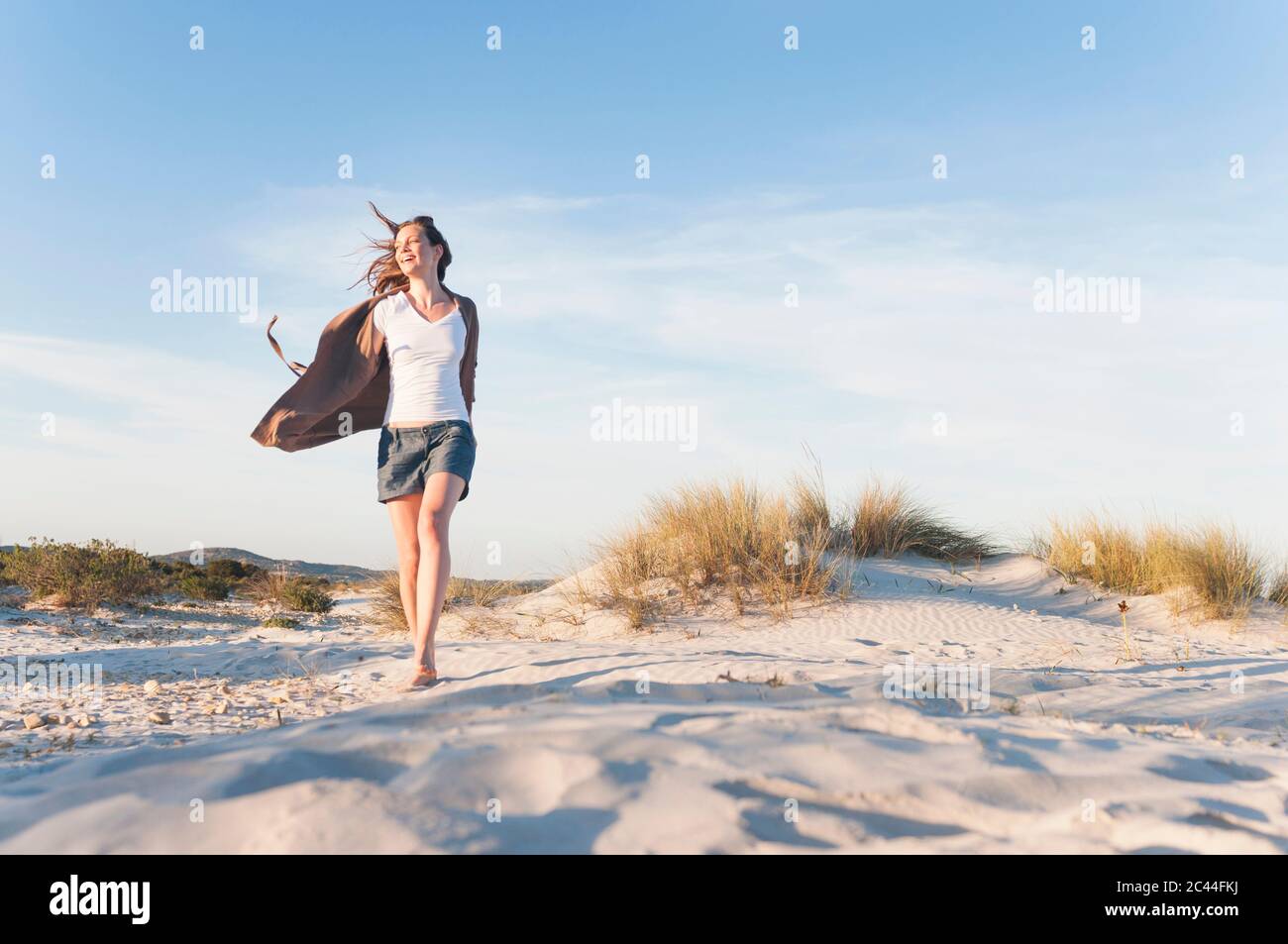 Glückliche Frau, die durch die Dünen am Strand schlendert, Sardinien, Italien Stockfoto