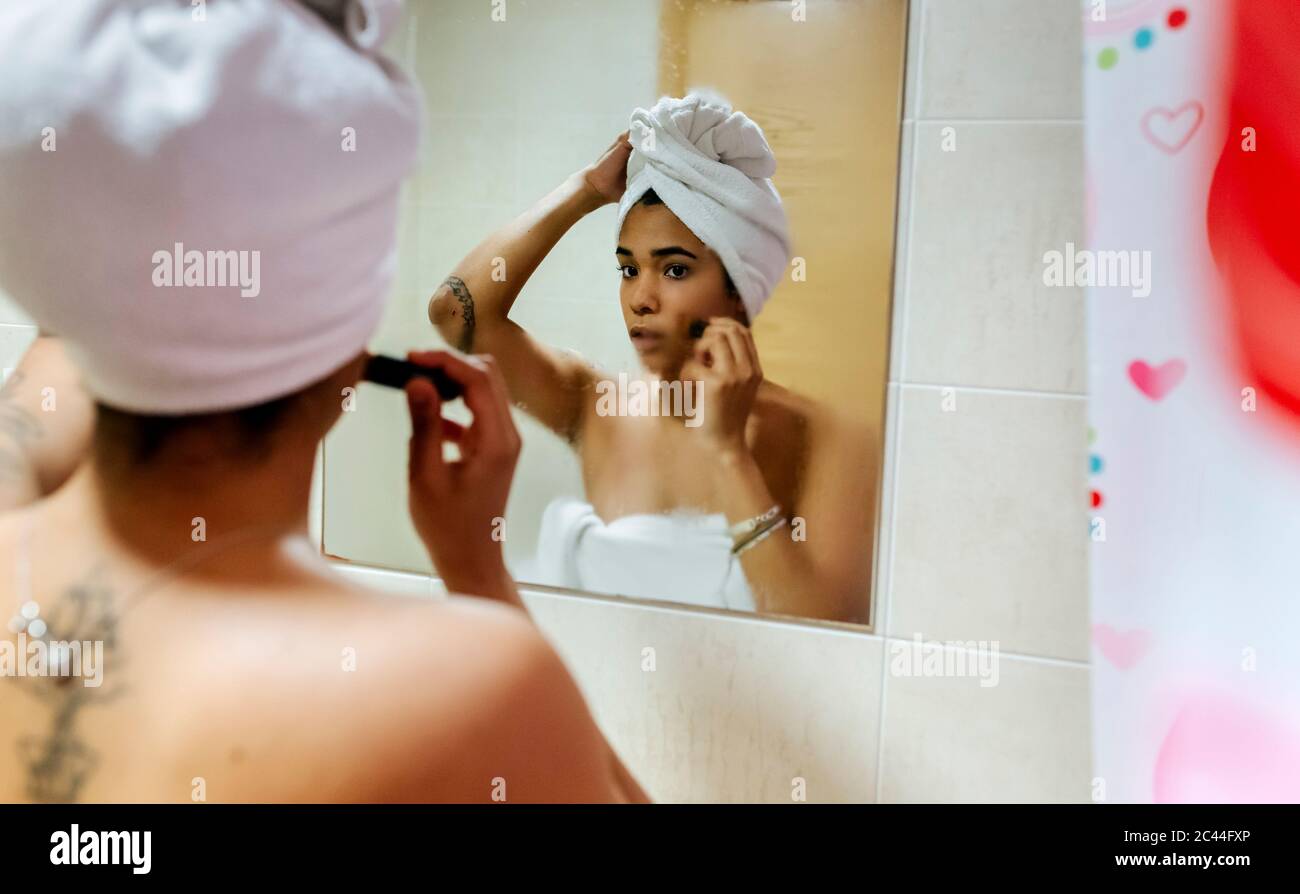 Junge Frau suchen im Badezimmer Spiegel Anwendung Make-up Stockfoto