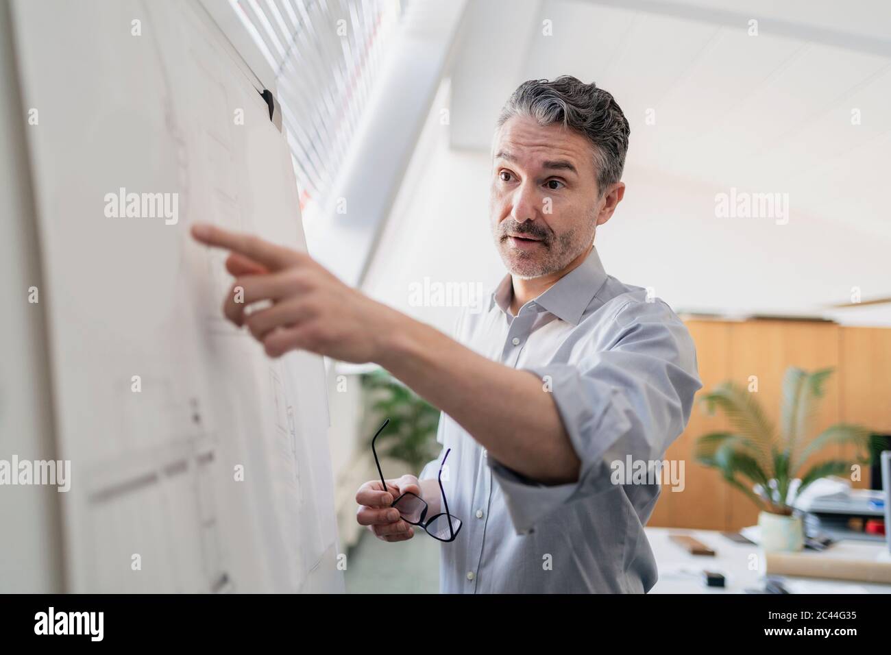 Selbstbewusste reife männliche Unternehmer zeigt auf Whiteboard während der Planung Strategie im Büro während der Sitzung Stockfoto
