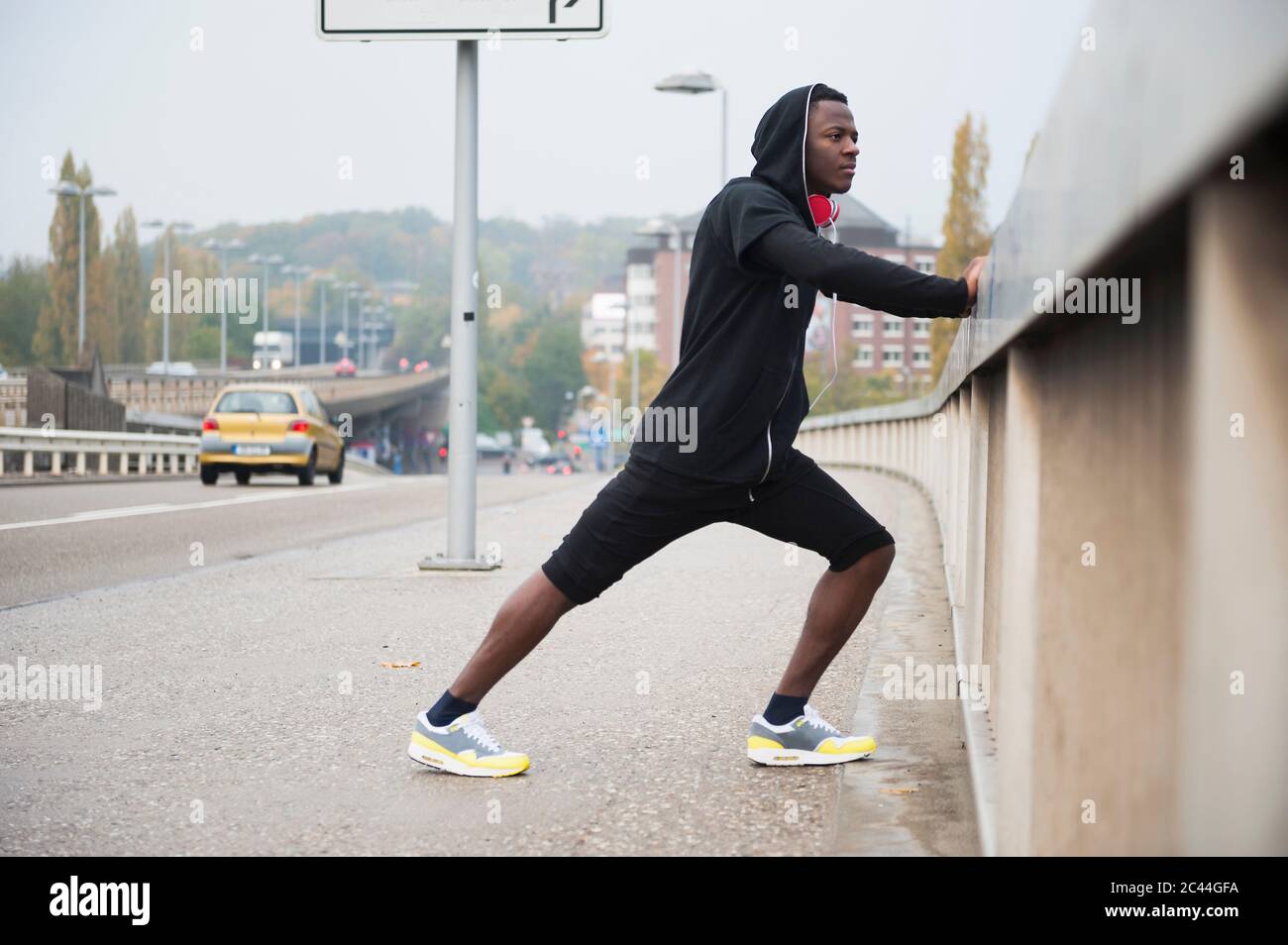 Junger Jogger, der sein Bein in der Stadt streckt Stockfoto