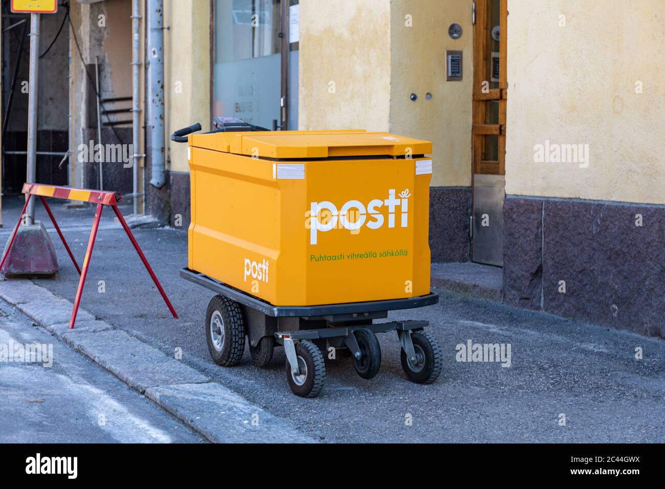 Moderner E-Mail-Trolley der finnischen Posti vor einem Wohnhaus in Helsinki, Finnland Stockfoto