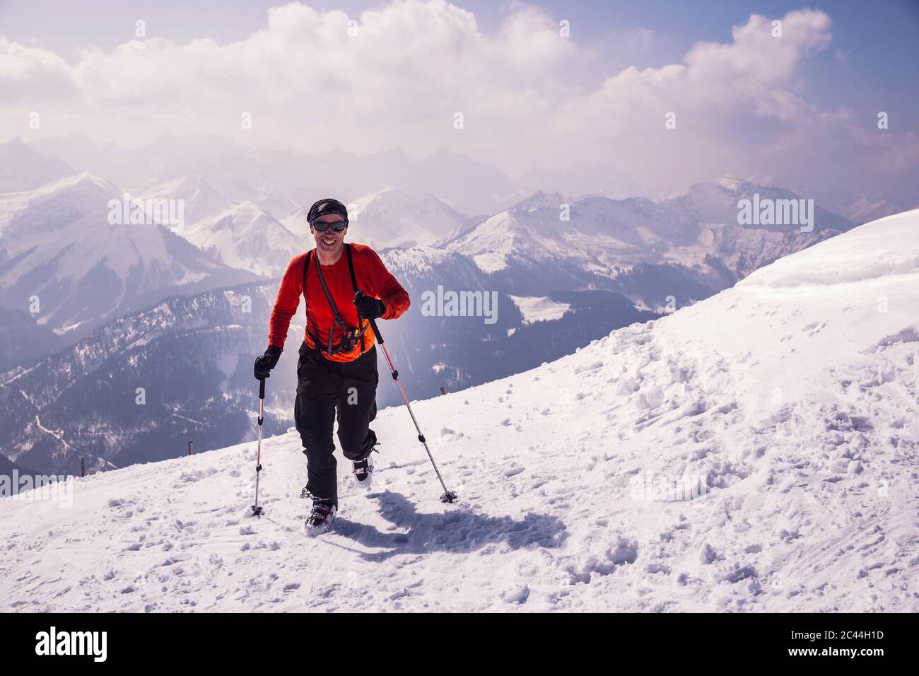 Voller glücklicher Mann läuft mit Skiern auf schneebedeckten Berg in Achenkirch, Tirol, Österreich Stockfoto