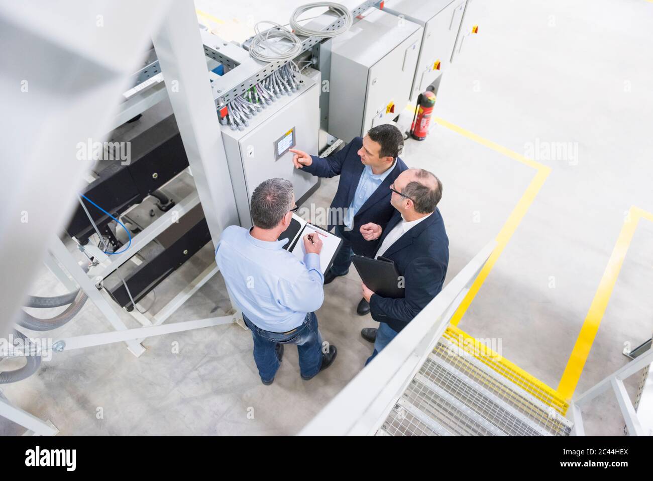 Drei Geschäftsleute, die in einer Fabrik diskutieren Stockfoto