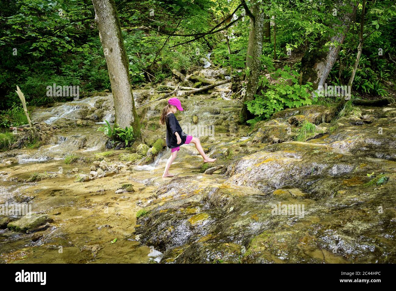 Volle Länge Seitenansicht des Mädchens zu Fuß barfuß auf natürlichen Bach im Wald Stockfoto