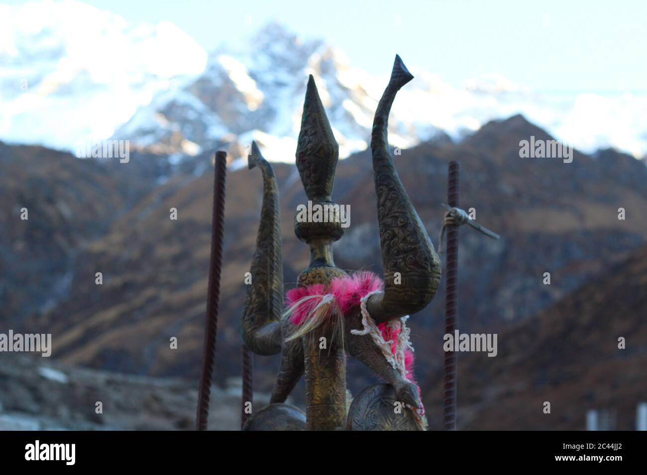 Ein Nahaufnahme Bild von Trishula (Waffe von lord shiva), mit einem verschwommenen Himalaya-Gipfel dahinter. Stockfoto