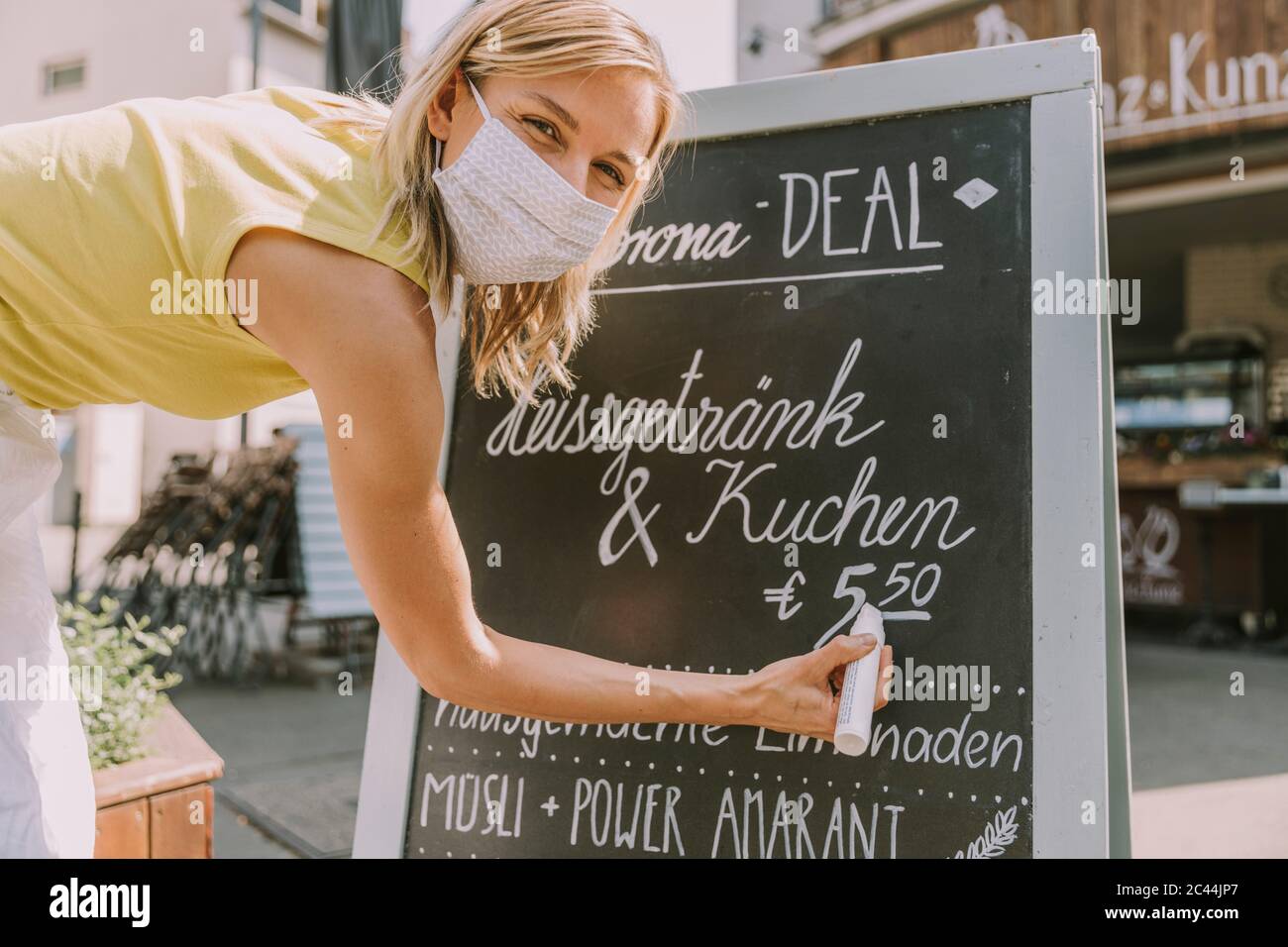 Cafe-Besitzer trägt Gesichtsmaske schreiben an Bord mit Corona Sonderangebote Stockfoto