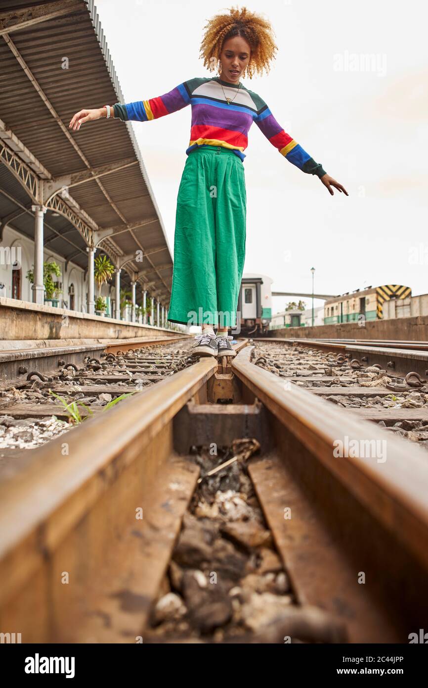 Ansicht der Oberfläche der jungen Frau, die auf Eisenbahnschienen gegen den Himmel geht Stockfoto