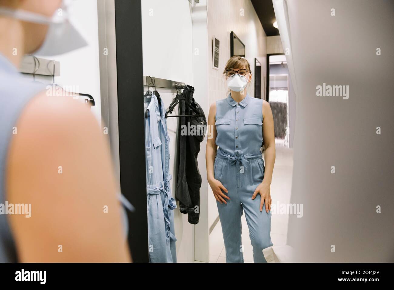 Frau mit Gesichtsmaske versucht auf Kleidung in einem Mode-Shop Stockfoto