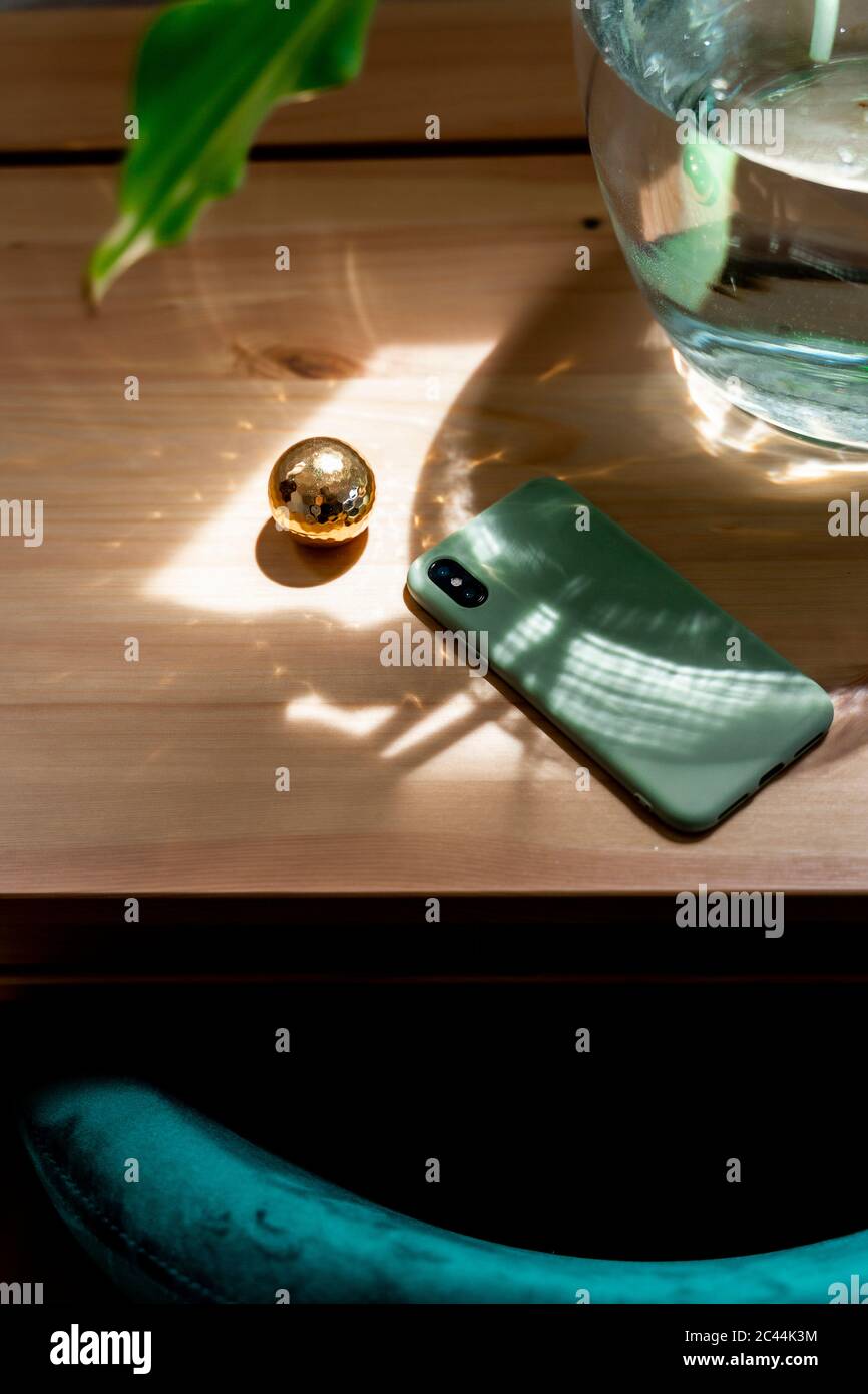 Handy von goldener Kugel auf Holztisch im Schlafzimmer zu Hause Stockfoto