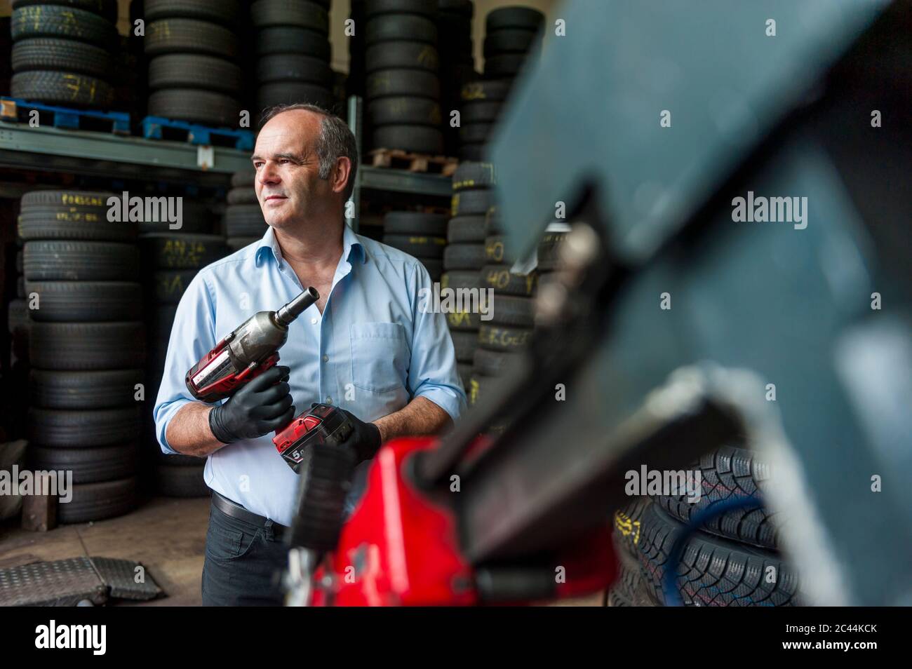Leitender Unternehmer hält Schlagschrauber, während Sie auf Reifen-Shop weg Stockfoto