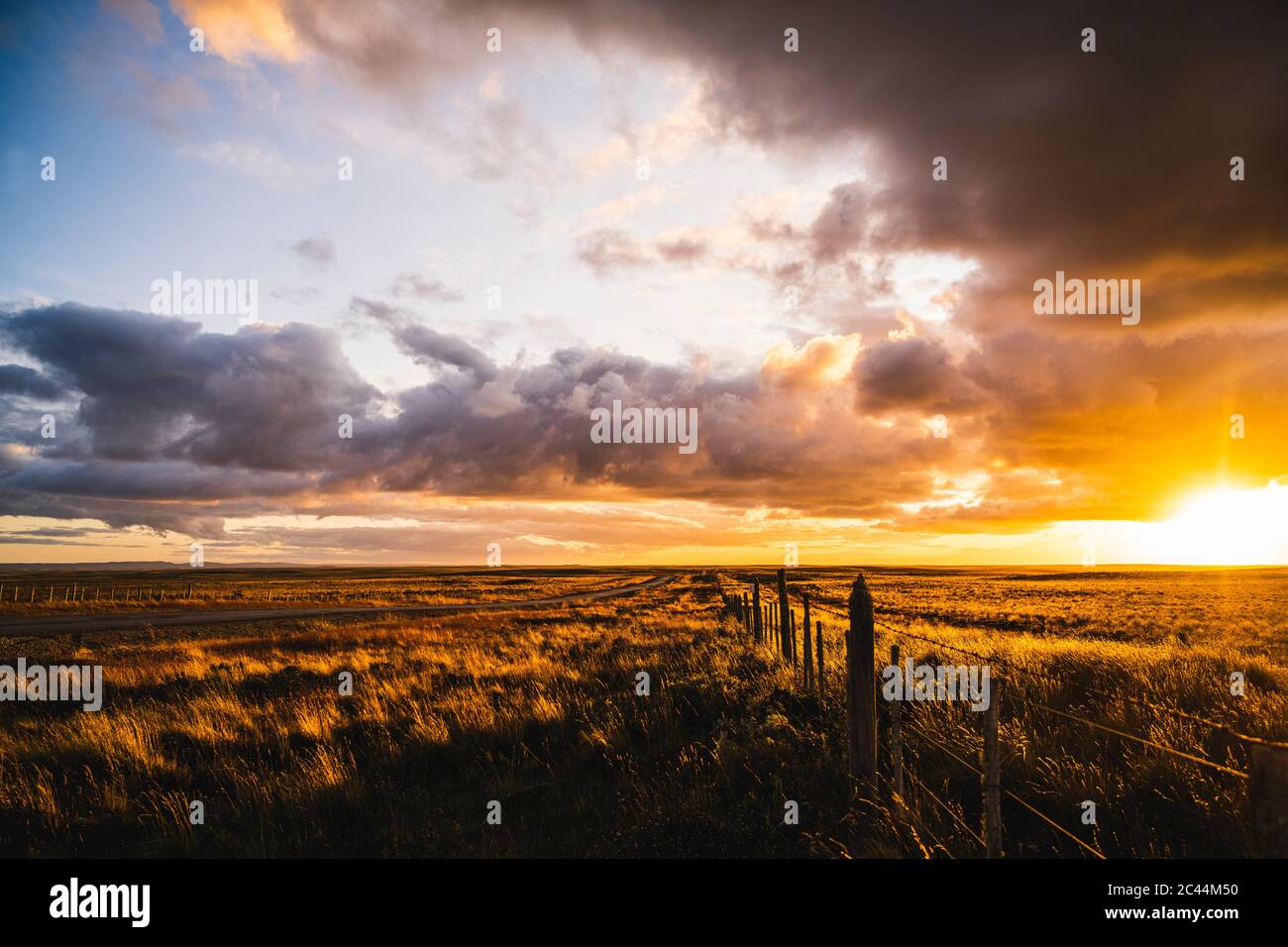 Chile, Zaun, der sich bei dramatischem Sonnenuntergang entlang des weiten Graslandes erstreckt Stockfoto