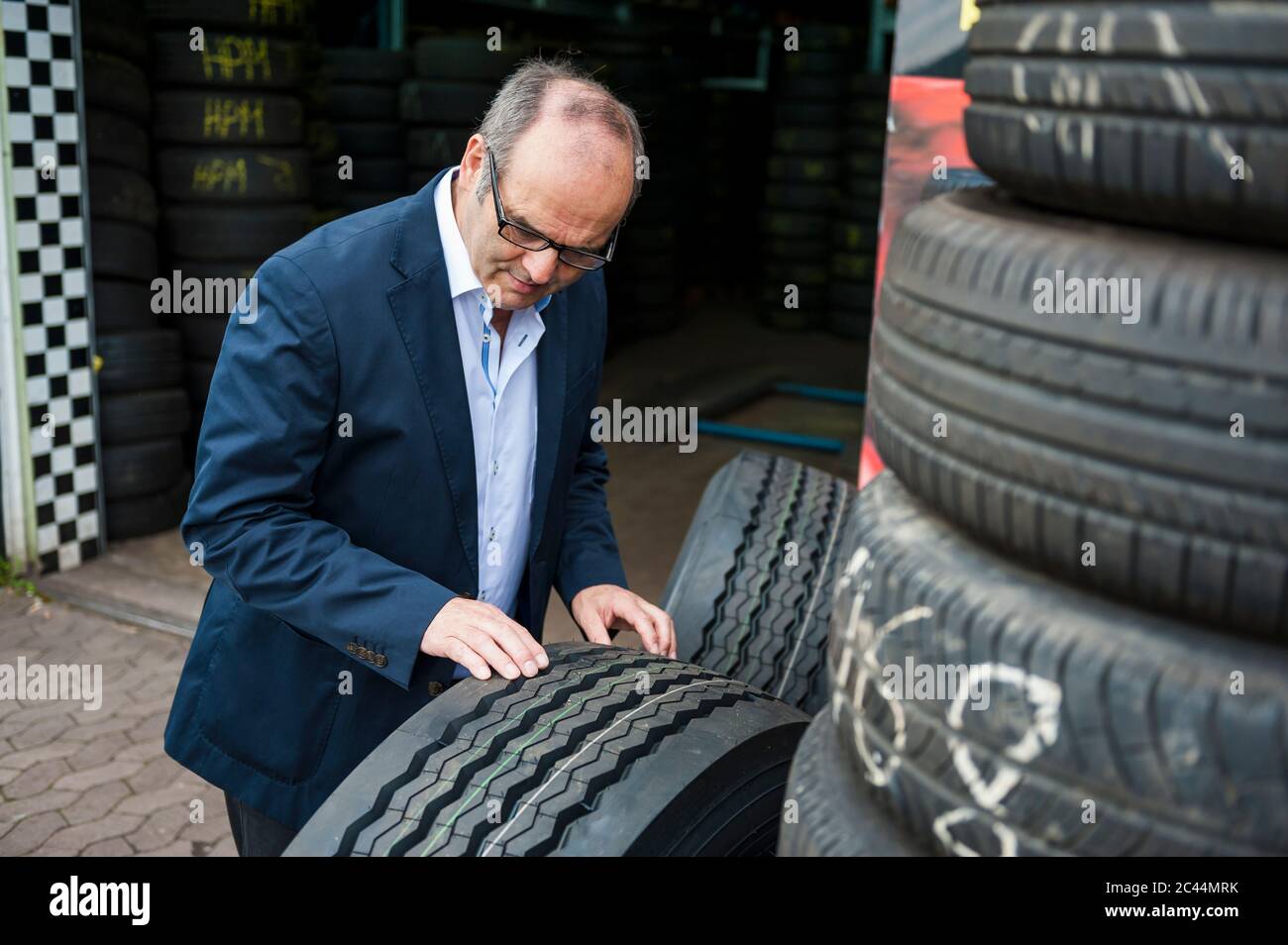 Älterer männlicher Besitzer, der Gummireifen im Geschäft überprüft Stockfoto