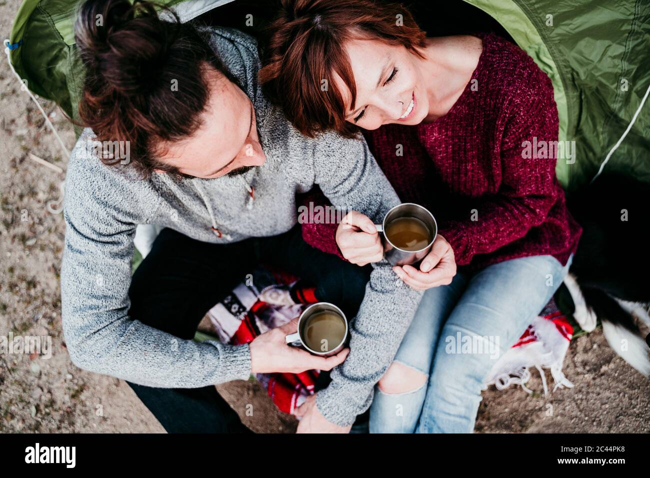 Glückliches Paar hält Tassen an einem Zelt Stockfoto