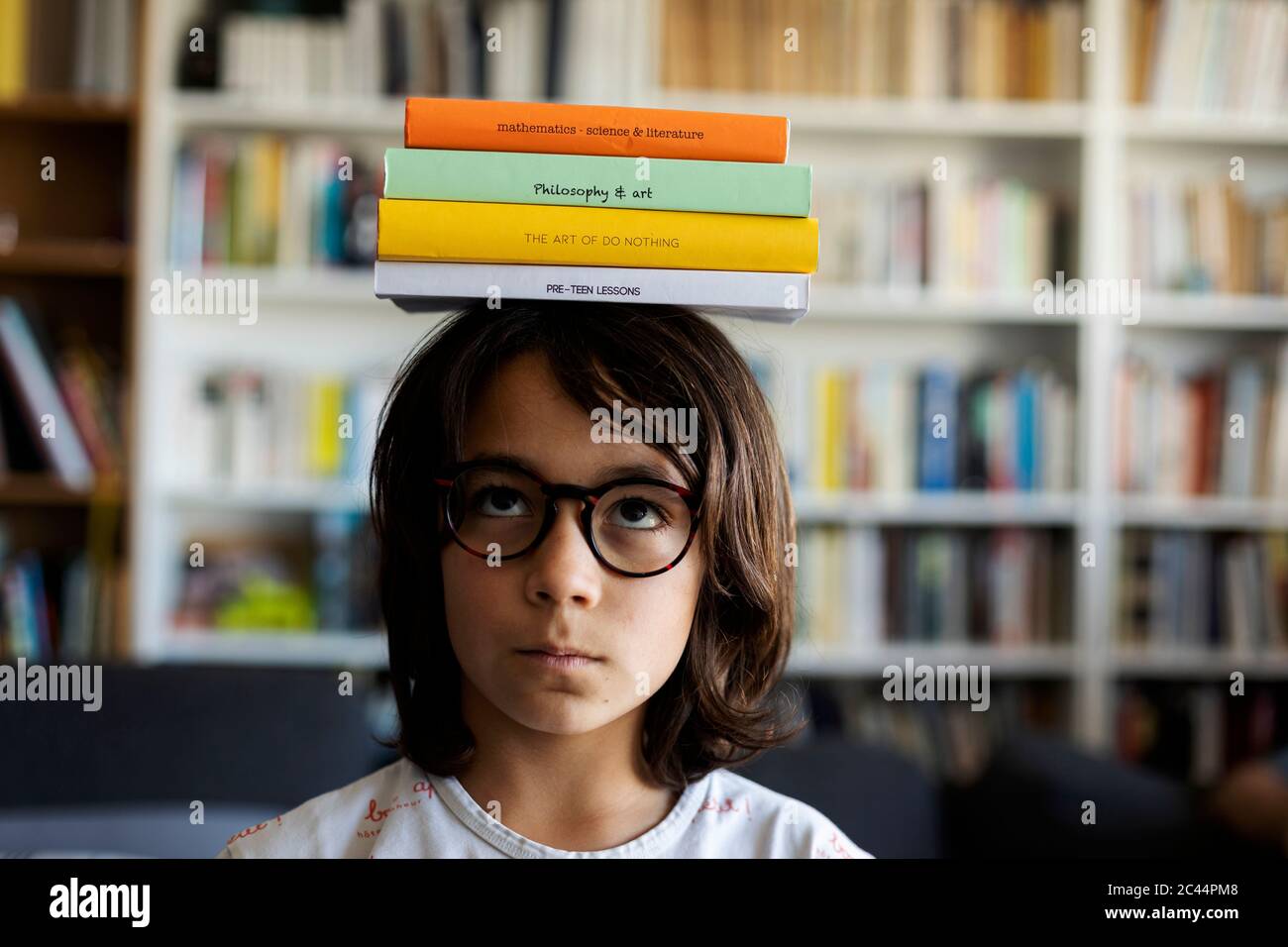 Portrait des Jungen balancieren Stapel von Büchern auf seinem Kopf Stockfoto
